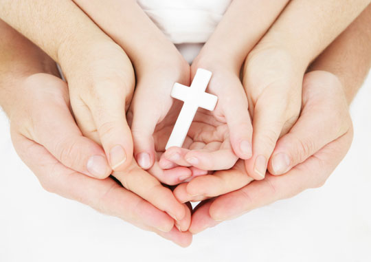 hands of adults and child holding cross - sharing faith