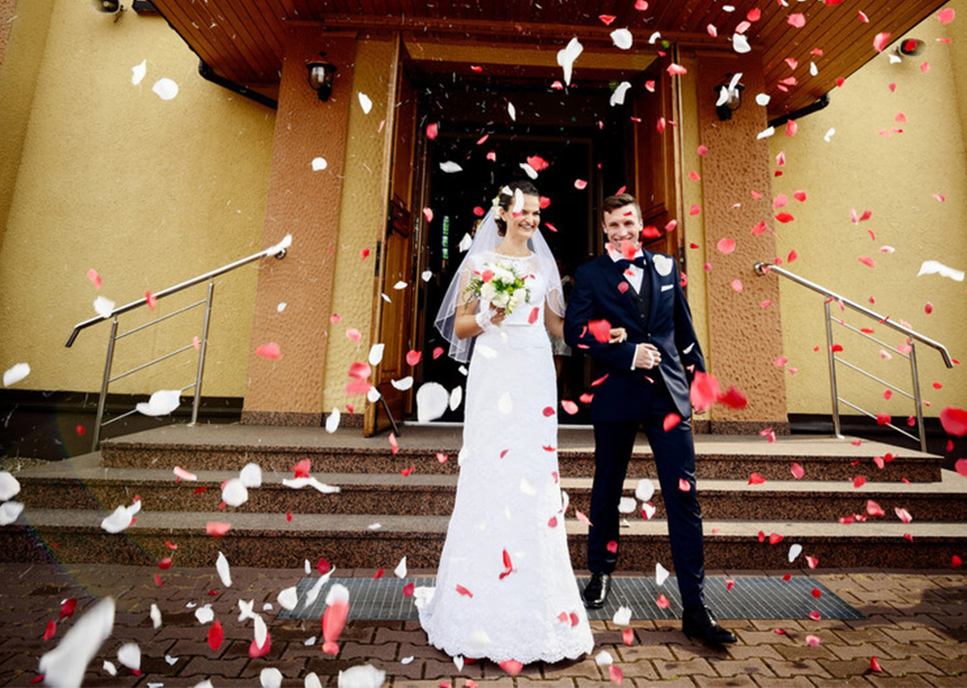 wedding couple walking out of church - djedzura/iStock/Getty Images