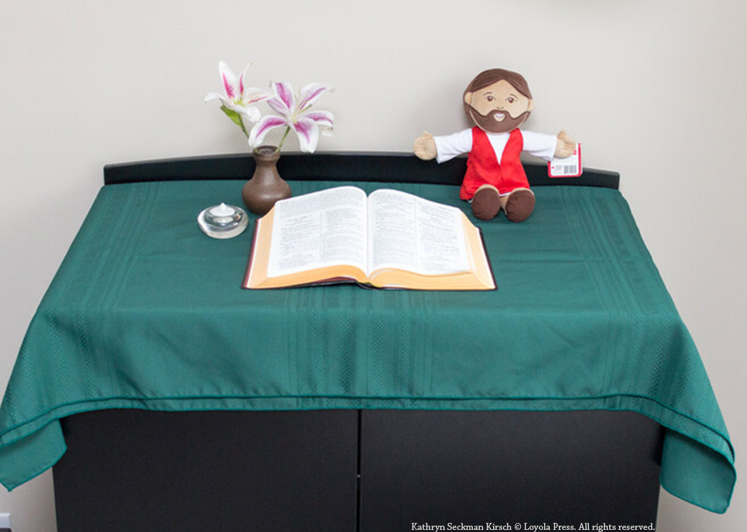 prayer table with green cloth, Bible, plush Jesus, water, and flower - Kathryn Seckman Kirsch © Loyola Press. All rights reserved.