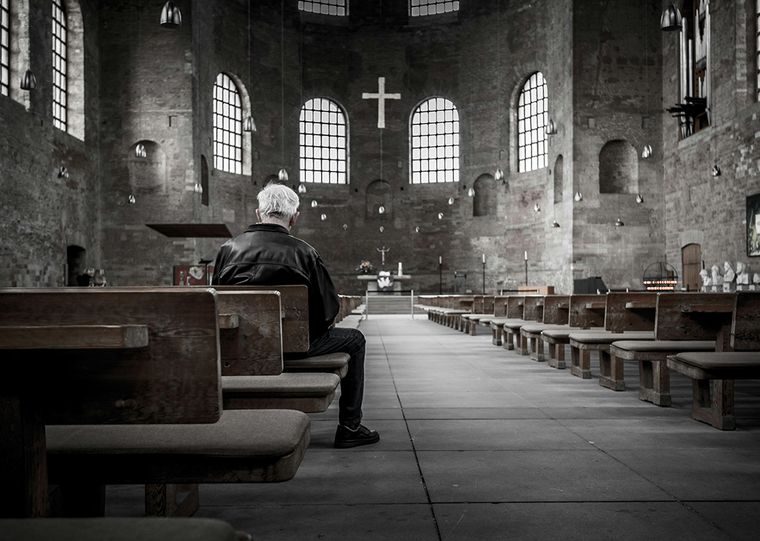 man praying in church - photo by Stefan Kunze on Unsplash