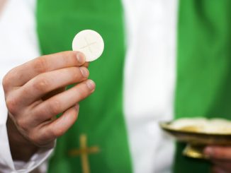 priest holding Communion host - Avalon_Studio/E+/Getty Images