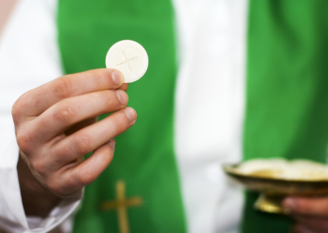 priest holding Communion host - Avalon_Studio/E+/Getty Images
