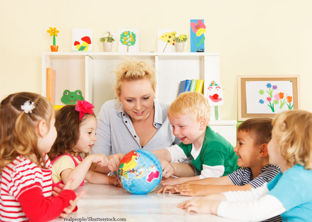teacher with young students looking at a globe - realpeople/Shutterstock.com