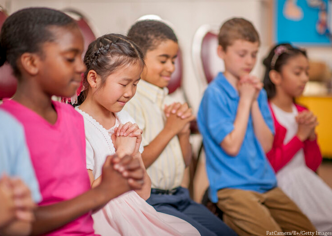 young children praying - FatCamera/E+/Getty Images