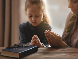 mother and daughter praying at home