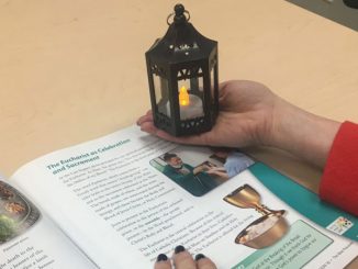 reading Finding God textbook while holding mini-lantern
