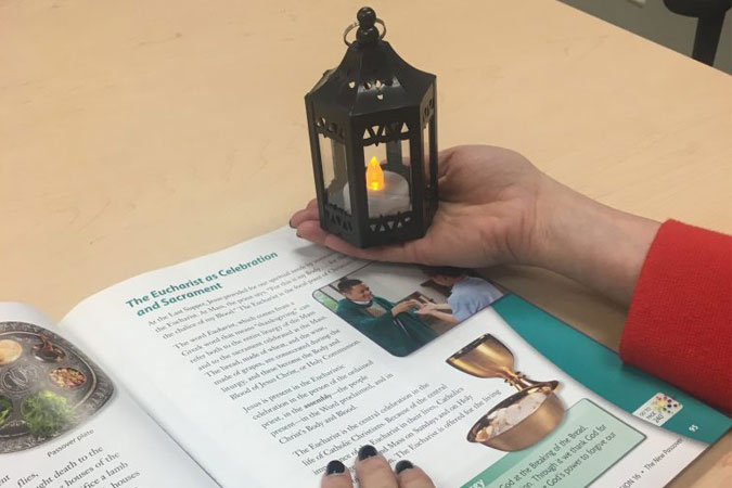 reading Finding God textbook while holding mini-lantern