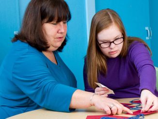 catechist and young person work on a craft project