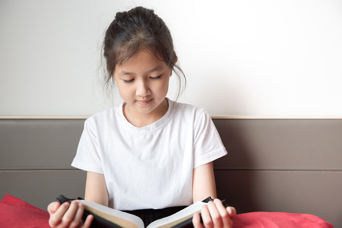 young girl reading Bible - Moosavefoto/Shutterstock.com